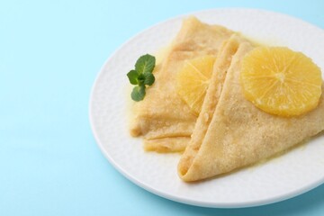 Delicious Crepes Suzette on light blue background, closeup