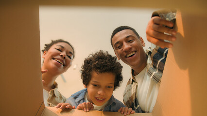 Point of view POV open box African american family parents son unpacking cardboard parcel happy funny little boy child kid surprise teddy bear toy birthday present moving day online shopping delivery