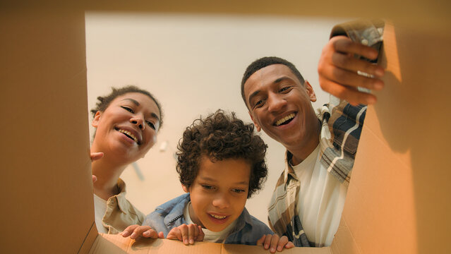 Point of view POV open box African american family parents son unpacking cardboard parcel happy funny little boy child kid surprise teddy bear toy birthday present moving day online shopping delivery - Powered by Adobe