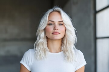 Naklejka premium A blonde beauty showcases her captivating presence in a spacious area, with a neutral gaze that invites interpretation and introspection against a backdrop of minimalist design.