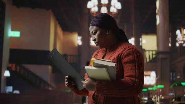 Female educator preparing her teaching materials and resources in the library, leveraging her expertise to mentor scholars and create a productive academic atmosphere for young minds. Camera A.