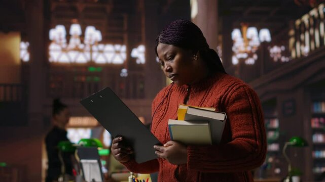 Female educator preparing her teaching materials and resources in the library, leveraging her expertise to mentor scholars and create a productive academic atmosphere for young minds. Camera B.
