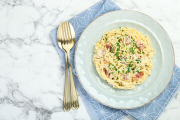 Delicious pasta Carbonara with bacon served on white marble table, flat lay