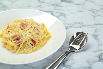 Delicious pasta Carbonara with bacon served on white marble table, closeup