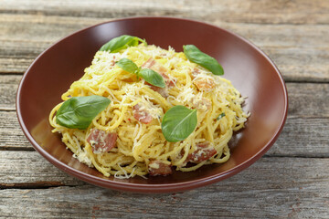 Delicious pasta Carbonara in bowl on wooden table, closeup