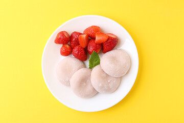 Delicious mochi and strawberries on yellow background, top view