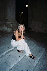 Tourist sitting on steps in italy at night enjoying her holiday trip