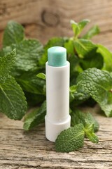 Natural lip balm and mint leaves on wooden background, closeup