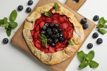 Tasty galette with berries and mint on white marble table, flat lay