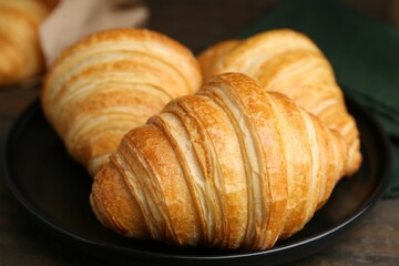 Tasty fresh croissants on wooden table, closeup. Puff pastry