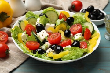 Delicious fresh Greek salad and ingredients on light blue wooden table, closeup