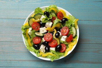 Delicious fresh Greek salad on light blue wooden table, top view