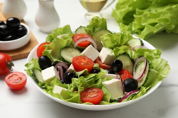 Delicious fresh Greek salad and ingredients on white marble table, closeup