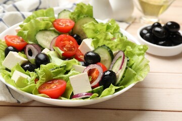 Delicious fresh Greek salad on light wooden table, closeup