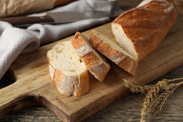 Pieces of fresh baguette and spikes on wooden table, closeup