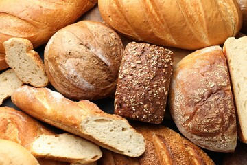 Whole and cut loafs of bread on table, closeup