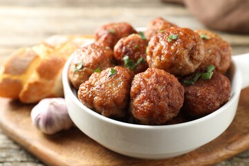 Tasty meatballs with green onion in baking dish on wooden table, closeup