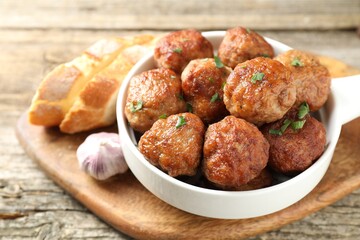 Tasty meatballs with green onion in baking dish on wooden table, closeup