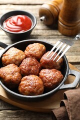 Tasty meatballs in baking dish served on wooden table, closeup