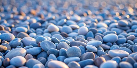 Obraz premium A close-up view of a field of smooth, rounded river stones, their blue-grey hues highlighted by the soft light of the setting sun, creating a serene and calming landscape.