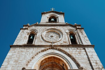Fototapeta premium A low-angle view of a historic church bell tower with intricate details against a vibrant blue sky