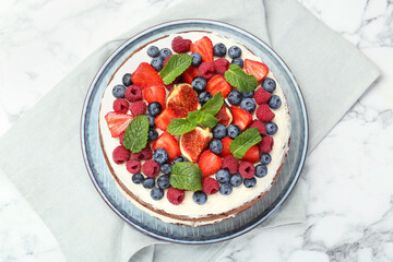 Delicious chocolate sponge cake with berries on white marble table, top view
