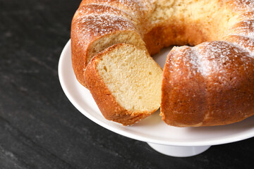 Freshly baked sponge cake on black table, closeup