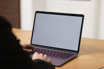 Businesswoman working with laptop at wooden table in office, closeup