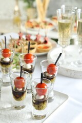 Many different tasty canapes and wine on white table, closeup