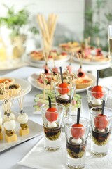 Many different tasty canapes on white table