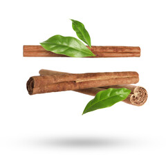 Cinnamon sticks and green leaves in air on white background
