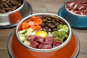 Dry pet food and natural products on wooden table, closeup