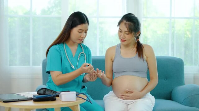 Asian nurse use glucometer to checking pregnant woman's blood sugar, giving a pin prick blood test to a pregnant female sitting on a sofa in home, Medicine, diabetes, glycemia, health care 