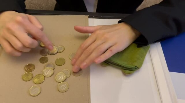 A man in a strict suit pours coins from his wallet into his hand and begins to count them carefully