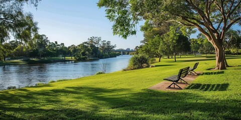 Obraz premium A serene park with benches by a river, surrounded by lush greenery and trees.