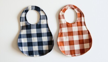 Two muslin bibs and a plaid neatly arranged on a white background, perfect for a baby feeding time.