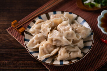 Eating fresh boiled dumpling using chopsticks with soy sauce.