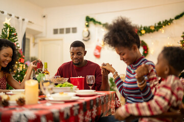 A warm Christmas family dinner with a father serving food to his young child, surrounded by festive decorations, a Christmas tree, and a holiday table spread. Joyful and cozy holiday atmosphere.