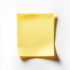 Bright yellow sticky note on a white background with soft shadows in a well-lit setting