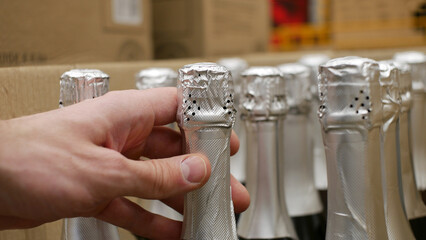 Close-up of a male customers hand taking a bottle of champagne or sparkling wine
