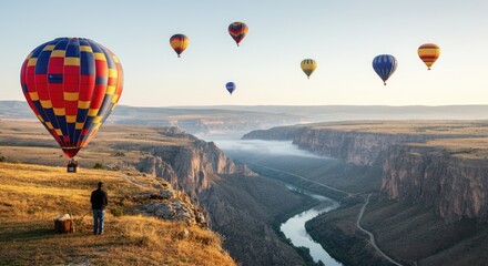 Fototapeta premium Nine multicolored hot air balloons floating over canyon with river below