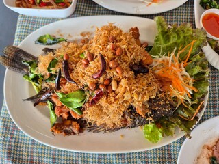 Deep fried Thai Nile Tilapia fish dressing with crispy shredded lemon grass serving on the plate. Famous local seafood menu in Thai restaurant.
