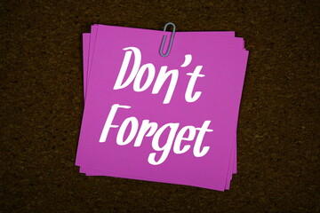 Don't Forget text on sticky note on cork board background