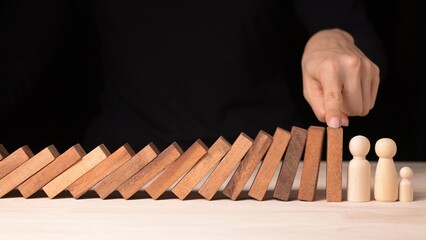 Naklejka premium Risk Management Strategies Hand Stopping Falling Dominos in Business Crisis Decision Making Conceptualized in a Controlled Environment
