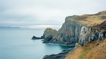 Serene coastal cliffs with calm waters under a cloudy sky.