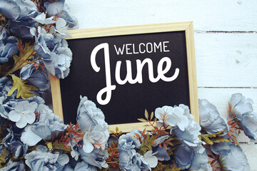 Welcome June text with flowers frame decoration top view on wooden background, © may1985