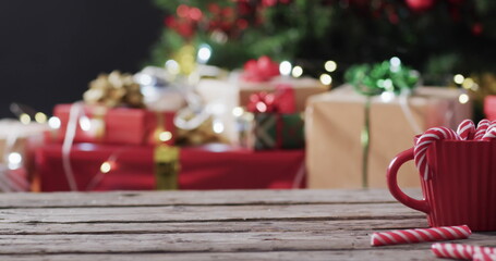 Merry christmas text in gold over candy canes and christmas presents