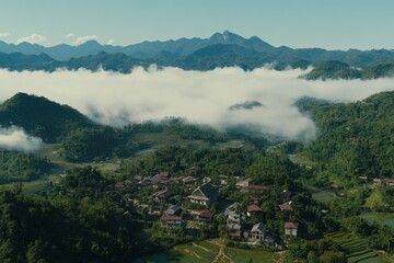 Naklejka premium A panoramic view of a Hmong tribal village nestled in terraced rice fields, with the morning mist rising over the surrounding hills