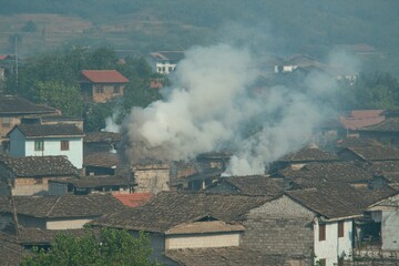 A peaceful evening shot of a Hmong village with smoke rising from the chimneys and the last rays of sunlight casting long shadows