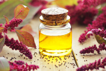 Amaranth seed oil or extract in glass bottle with  grain on wooden table, closeup, natural medicine and healthy skin and body treatment concept